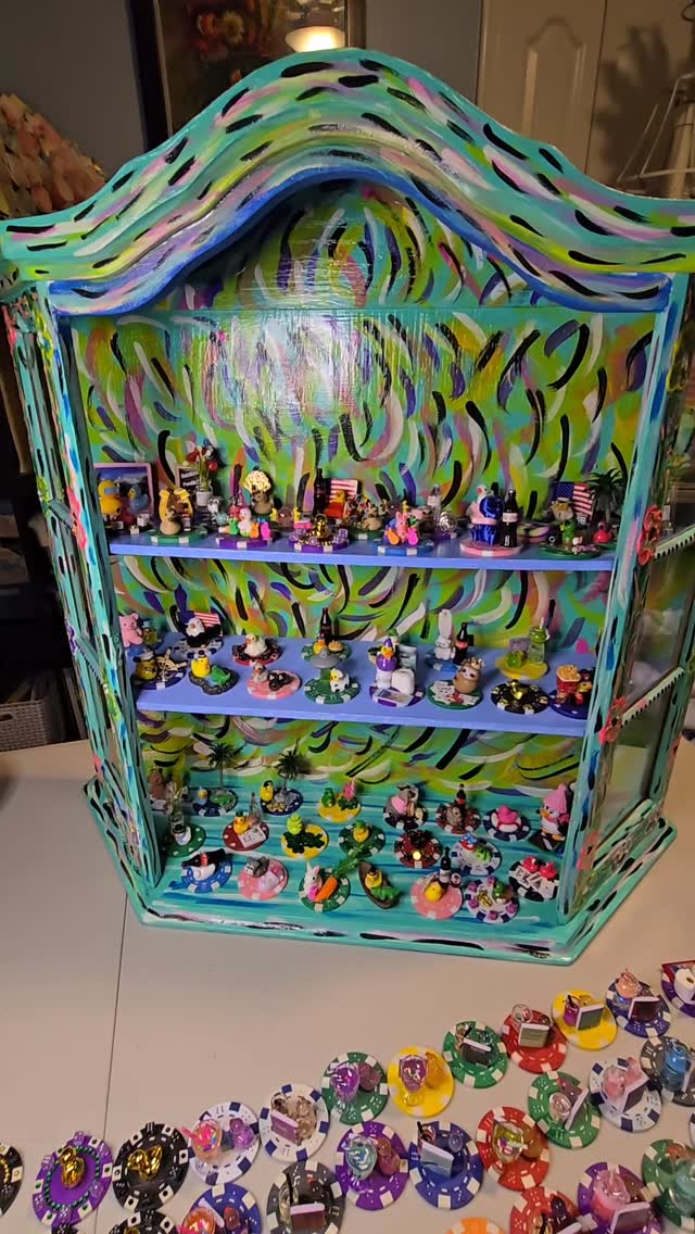 A painted display cabinet filled with shelves of poker chip ducks